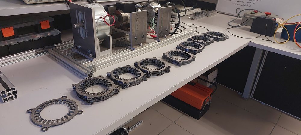 Stator laminations laid out next to a test rig at EMDLab